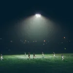 Partido de futbol nocturno en cancha iluminada