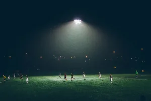 Partido de futbol nocturno en cancha iluminada