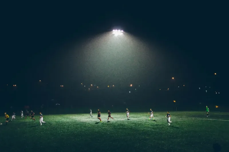 Partido de futbol nocturno en cancha iluminada