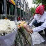 Persona coloca flores afuera del bar Rong Beer Na Ladprao tras el incendio en Bangkok