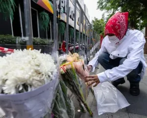 Persona coloca flores afuera del bar Rong Beer Na Ladprao tras el incendio en Bangkok