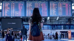 Pasajera consulta un tablero de vuelos dentro de un aeropuerto