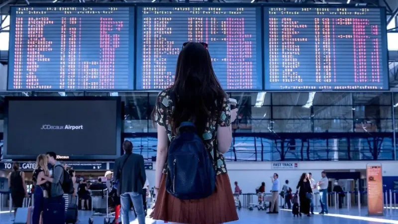 Pasajera consulta un tablero de vuelos dentro de un aeropuerto
